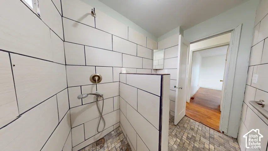 White subway tile shower with bronze fixtures and mosaic tile flooring