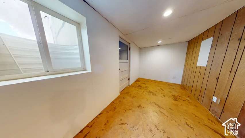 Wood paneling accent wall, white painted walls, recessed lighting, white framed window, and a paneled door