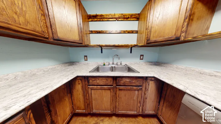U-shaped kitchen layout featuring wood cabinetry, stainless steel double basin sink, and ample counter space