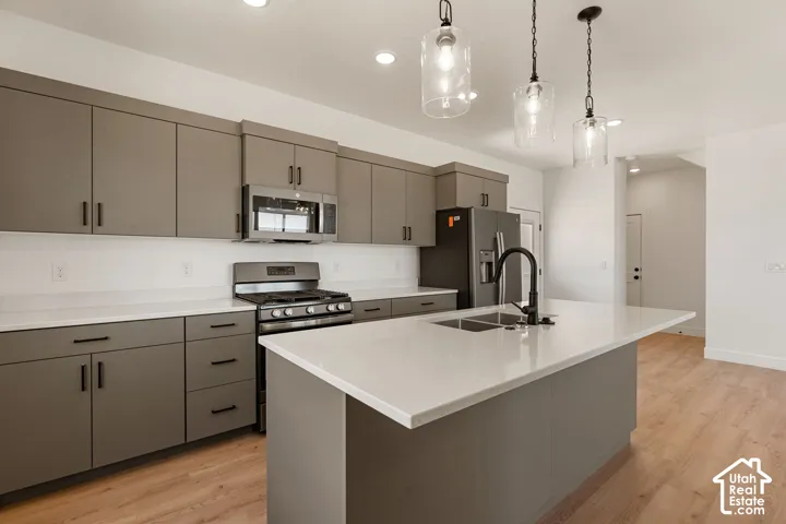Kitchen featuring a center island, light-toned countertops, modern cabinetry with dark hardware, and stainless steel appliances