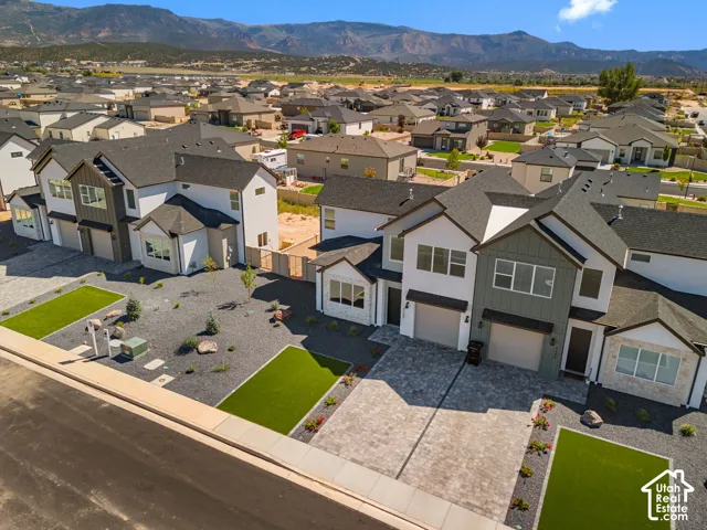 Modern exterior with varied siding textures, attached garage, paver driveway, and low-maintenance landscaping with artificial turf