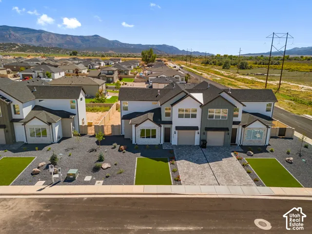 Contemporary two-story exterior with a two-car garage, gray siding accents, and a stone-paver driveway