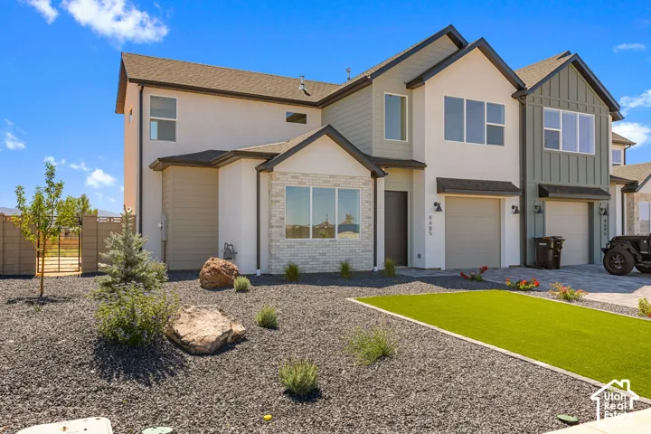 Contemporary exterior design featuring stucco siding, vertical board and batten accents, and light-toned brickwork