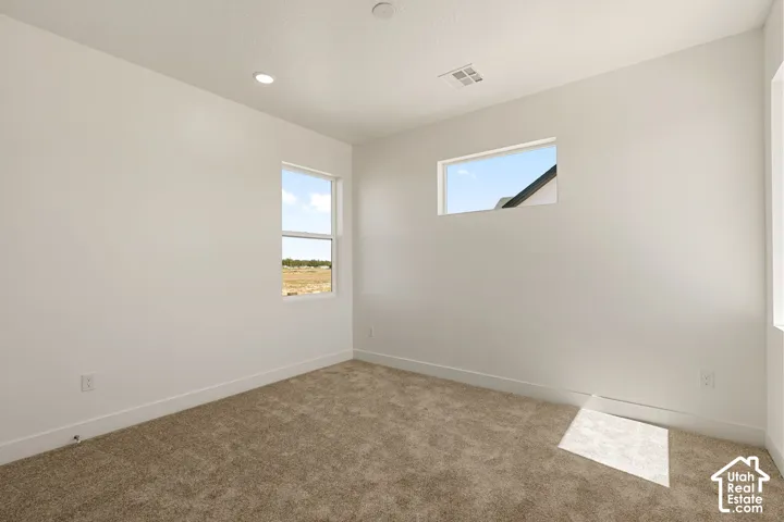 Recessed lighting, broadloom carpeting, crisp white walls, and multiple windows