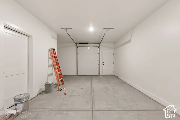Spacious garage featuring a concrete floor, overhead lighting, an overhead garage door, and an interior access door