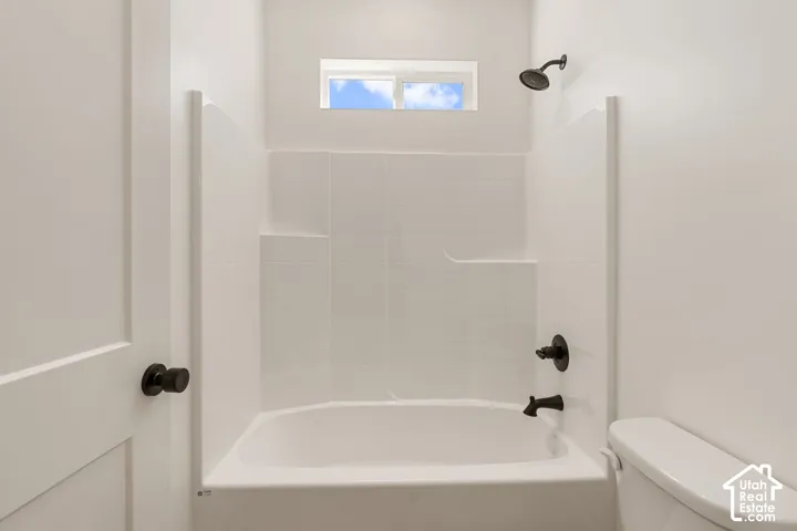 White tub shower combination with matte black fixtures and a small transom window