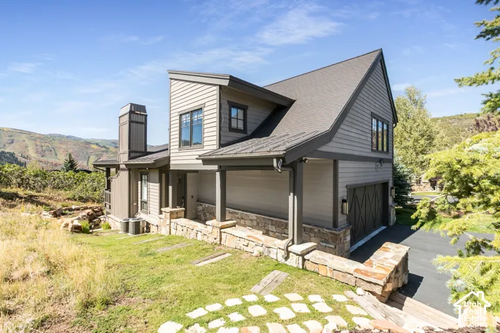 Multi-level residence featuring gray siding, a charcoal shingle roof, and stone accents