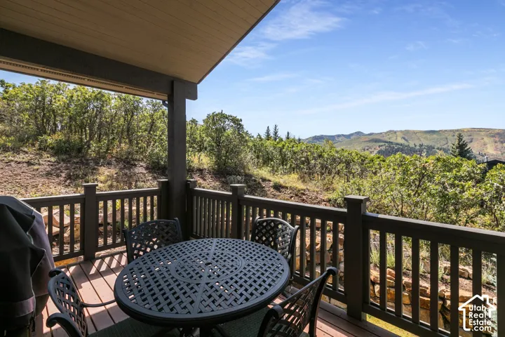 Expansive outdoor deck with wood-finish flooring, dark wood railings, and a covered ceiling
