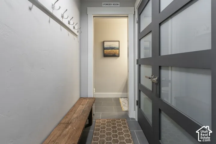Hallway featuring stone tile flooring and a modern paneled door with frosted glass