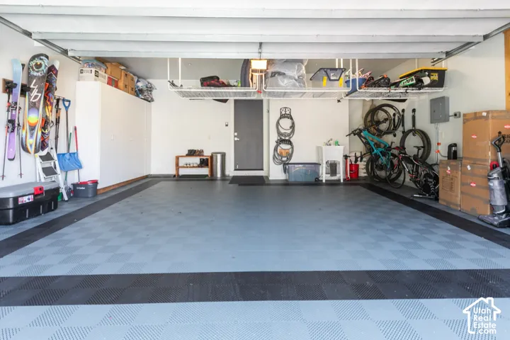 Durable checkerboard-patterned flooring, built-in overhead storage racks, white storage cabinets, and a solid-core door