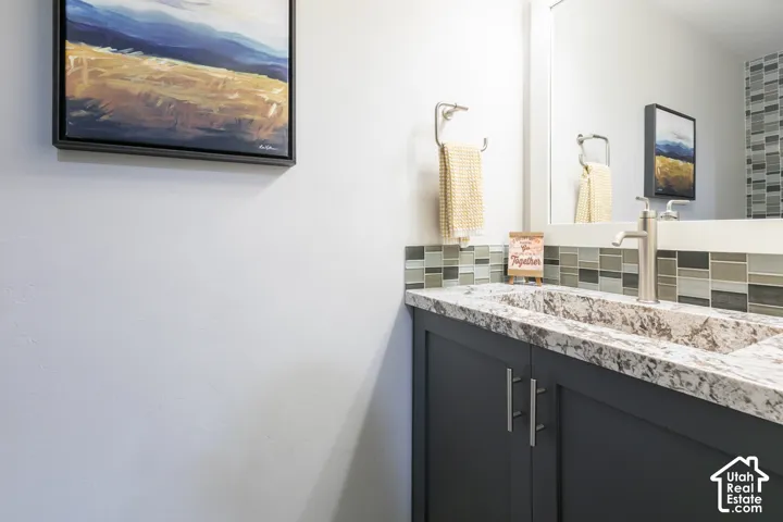 Integrated vanity with a stone-finish countertop and sink, dark cabinetry, and brushed nickel hardware