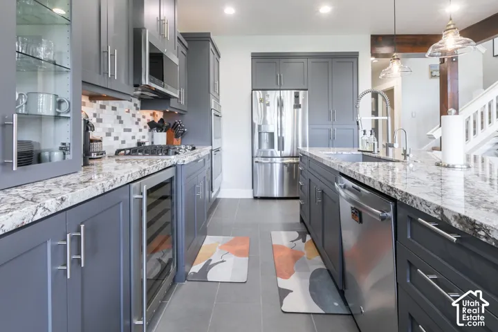 Stainless steel appliances, granite countertops, gray shaker cabinetry, mosaic tile backsplash, and recessed lighting