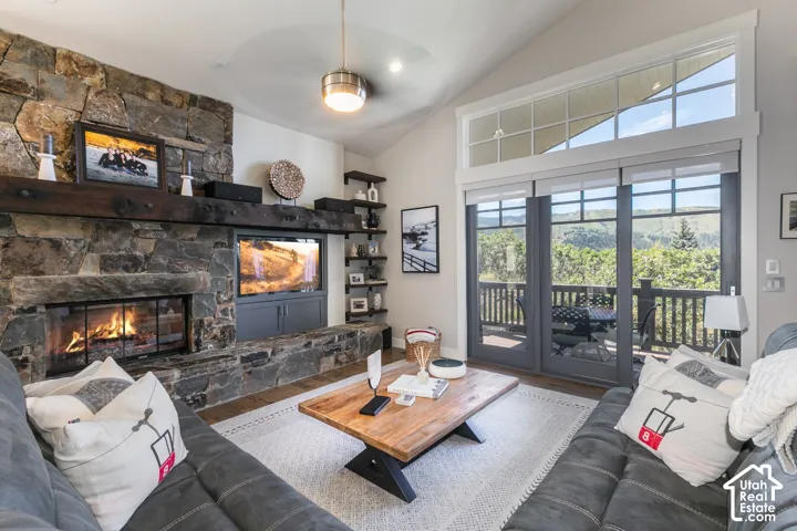 Stone-clad fireplace with built-in media cabinet, vaulted ceiling, and transom windows