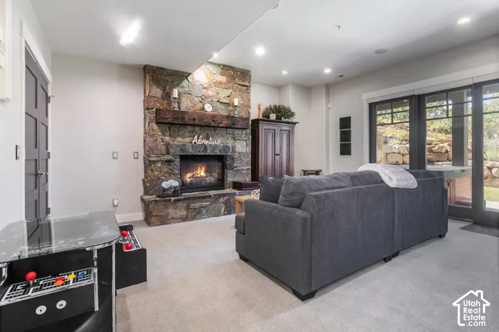 Stone-clad fireplace with a wood mantel, recessed lighting, and large sliding glass doors