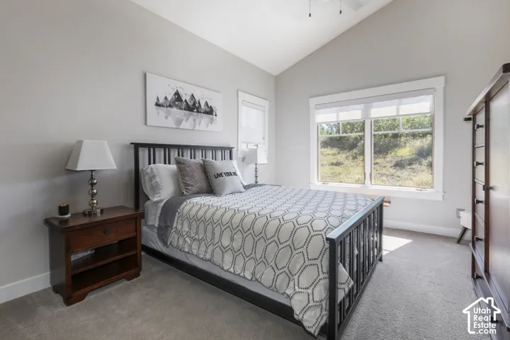 Vaulted ceiling, ceiling fan, large window with natural light, light gray wall color, neutral carpeting