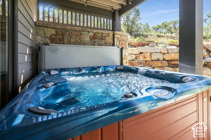 Outdoor spa with bubbling water, stone wall surround, and wood paneling