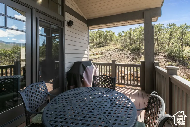 Covered outdoor deck with wood-finish flooring, a wood-slat railing, and a sliding glass door
