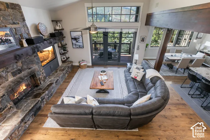 Vaulted ceiling great room with a stone-clad fireplace and wood mantle