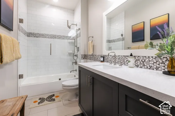Tub-shower combination with glass enclosure, white subway tile surround, and mosaic accent band