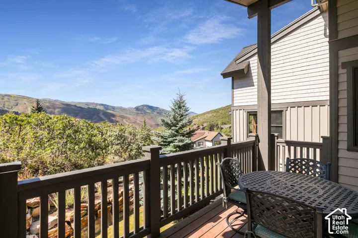 Outdoor wood-finish deck with dark railings, siding exterior, and a natural mountain backdrop