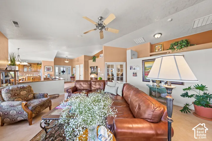 Vaulted ceiling with a ceiling fan, light wood-finish flooring, and built-in display shelving