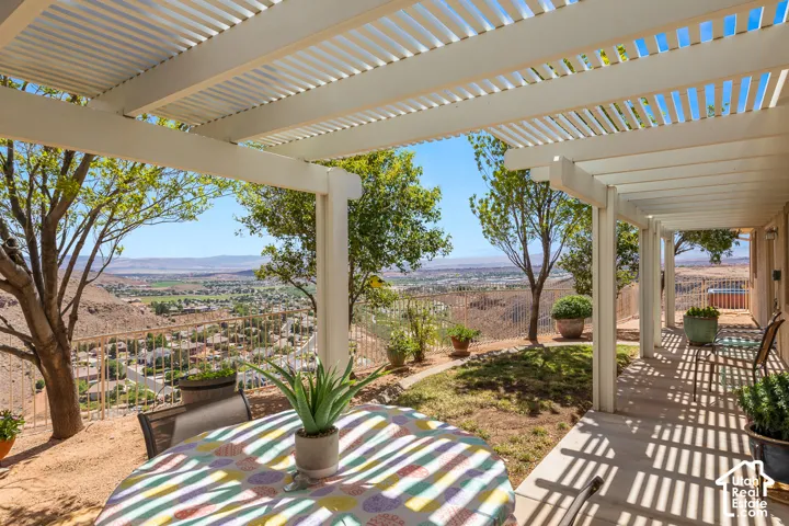 Expansive outdoor patio with a slatted pergola cover, offering an elevated desert landscape
