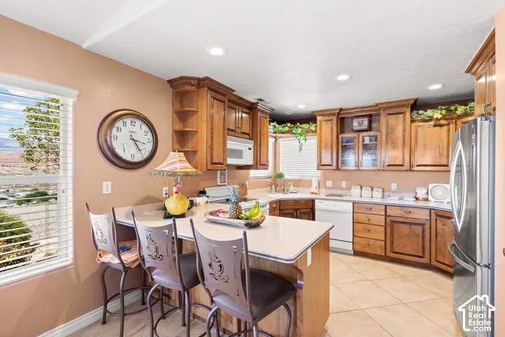 Kitchen featuring wood cabinetry, integrated appliances, recessed lighting, and tile flooring