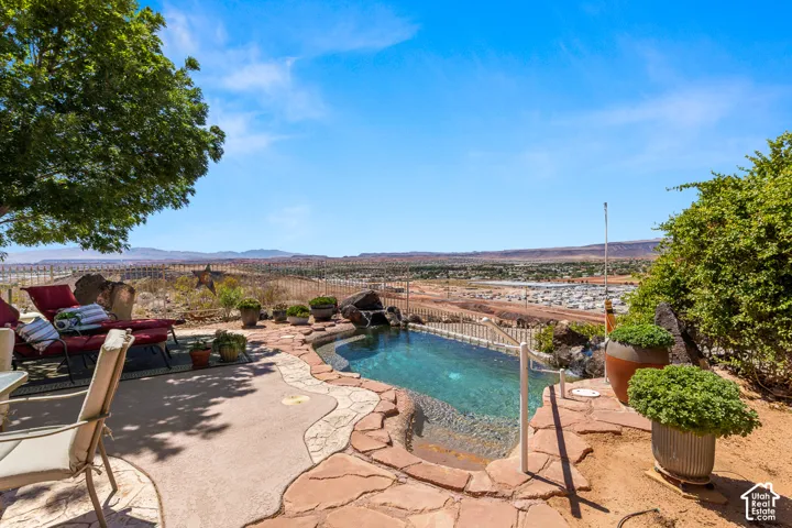 Private outdoor living area with a built-in swimming pool, stone coping, and a surrounding paver patio