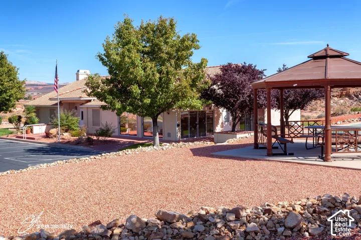 Red rock landscaping with a built-in gazebo featuring a picnic table and benches