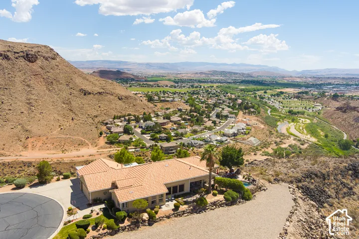 Tile roof residence with a cul-de-sac driveway, surrounded by arid landscaping and distant green spaces
