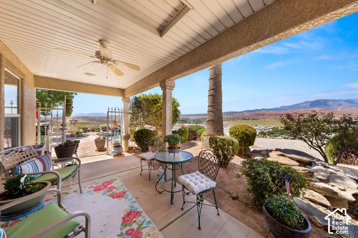 Covered patio with a ceiling fan, textured columns, and a concrete surface