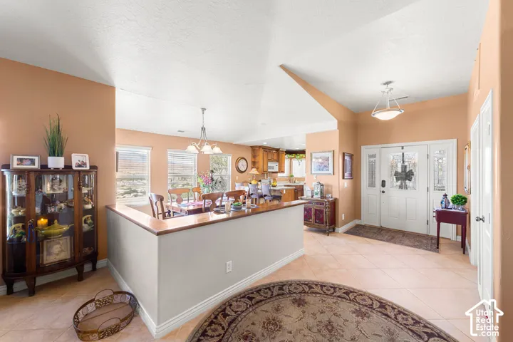 Double entry doors with decorative glass panels, tile flooring, vaulted ceilings, recessed lighting, and a partial wall divider with a wood-finish cap