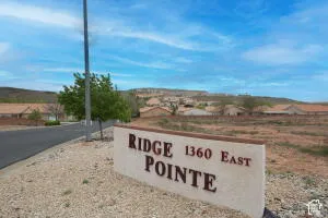 Monument signage at the community entrance featuring stone-finish wall and desert landscape backdrop