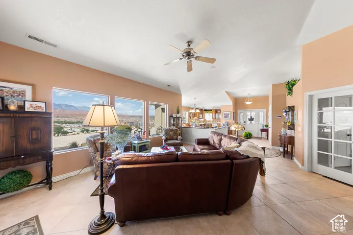 Vaulted ceilings with a ceiling fan, expansive windows, tile flooring, and a French door