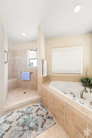 Walk-in shower with tiled walls and built-in bench, corner soaking tub with tiled surround, and recessed lighting