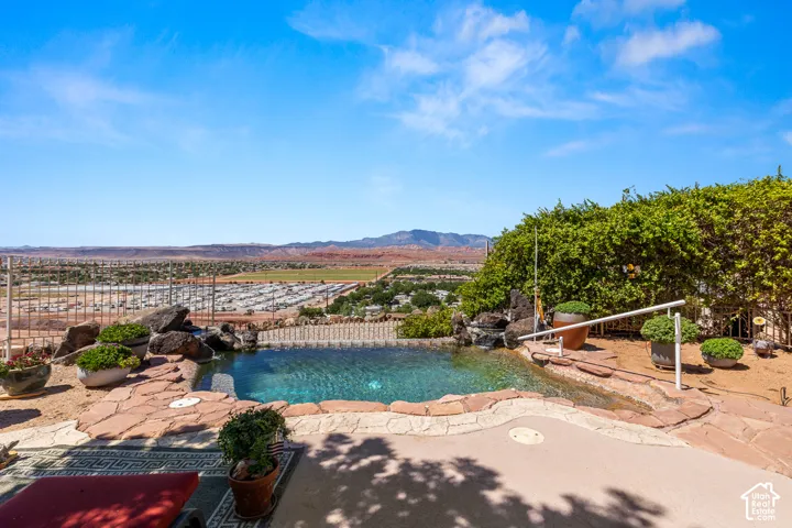 Infinity-edge pool featuring a rock waterfall, flagstone coping, and integrated handrails