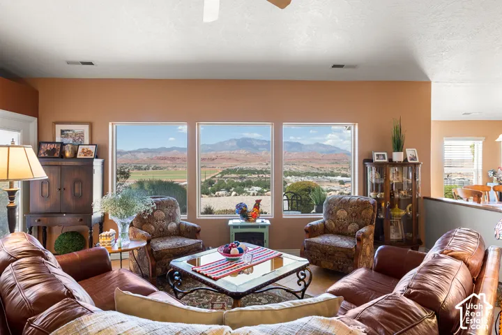 Living area with three large windows providing expansive scenery, wood-finish flooring, and a ceiling fan