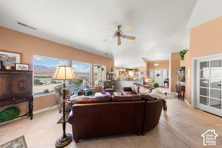 Vaulted ceilings with a ceiling fan, expansive windows, tile flooring, and a French door