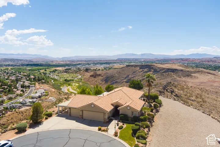 Terracotta roof tiles, attached garage, circular driveway, desert landscaping, and distant mountain scenery
