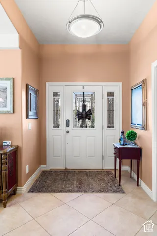Entryway featuring a white door with decorative glass inserts, flanking sidelights, and a transom window