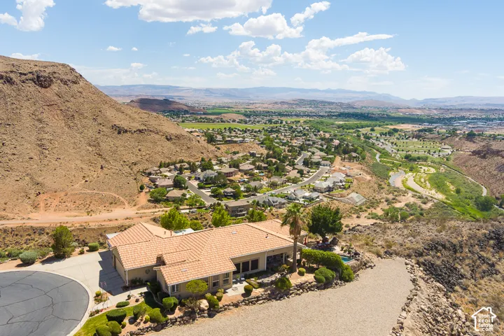 Tile roof residence with a cul-de-sac driveway, surrounded by arid landscaping and distant green spaces