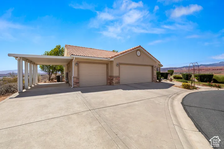 Stucco exterior with a tile roof, dual garage doors, a covered carport, and a concrete driveway
