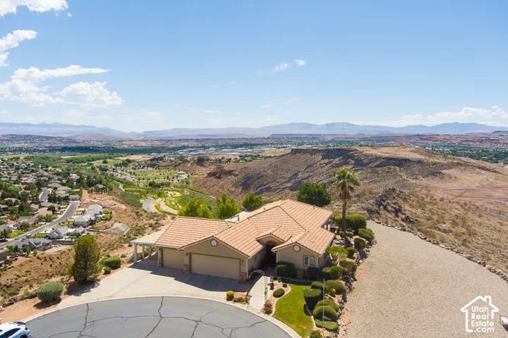 Terracotta roof tiles, attached garage, circular driveway, desert landscaping, and distant mountain scenery