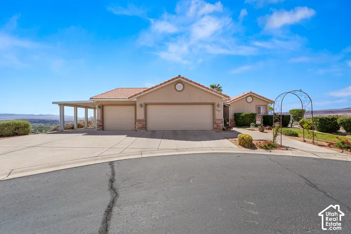 Stucco exterior with a tile roof, two-car garage, and an attached carport