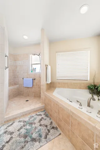 Walk-in shower with tiled walls and built-in bench, corner soaking tub with tiled surround, and recessed lighting