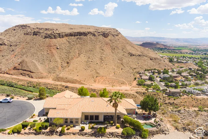 Expansive desert mountain backdrop with a residential community, cul-de-sac, and landscaped property featuring a structured patio with a built-in spa