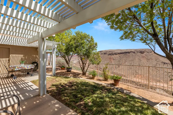 Expansive outdoor patio with a slatted pergola, durable concrete flooring, and a low-maintenance fenced yard