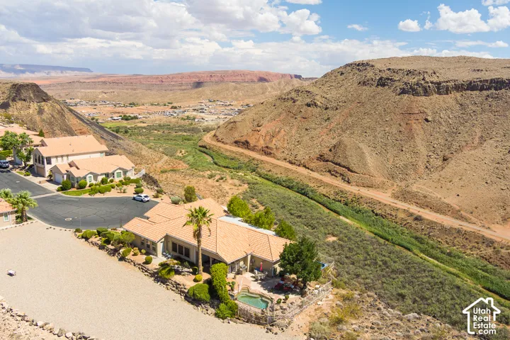 Terracotta tile roof home with an integrated pool and spa, surrounded by desert landscaping, with a prominent desert canyon backdrop featuring a riverbed