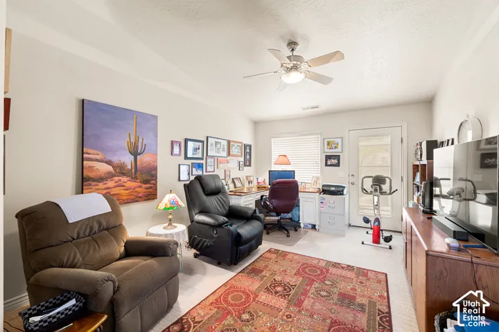 Room featuring a ceiling fan with integrated lighting, wood-finish flooring, and a glass-paneled door