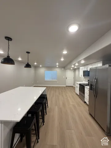 Open concept living space featuring wood-finish flooring, recessed lighting, and a kitchen island with a light-toned countertop